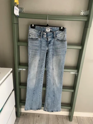 Ljusblå bootcut jeans från 157 - Säljer ett par ljusblå bootcut jeans från 157 med dubbla knappar i midjan och markerade sömmar framtill. Jeansen har klassisk femficksmodell och är tillverkade i denim med lätt tvättad look. Perfekta för en avslappnad och trendig stil.