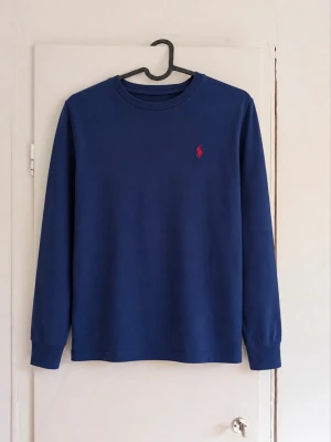 Ralph Lauren tröja - Klassisk mörkblå långärmad tröja med röd broderad logga på bröstet. Enkel och stilren modell som är lätt att matcha till både jeans och chinos. Fint begagnat skick, den har inga defekter!  Skriv gärna vid frågor eller om du vill ha fler bilder! 💌