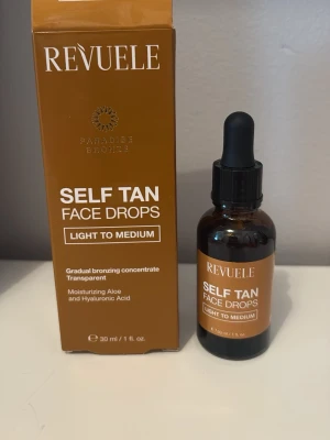 Revuele Self Tan Face Drops Light to Medium - Brun-utan-sol droppar för ansiktet från Revuele i nyansen Light to Medium. Kommer i en brun glasflaska med pipett och matchande förpackning. Innehåller återfuktande aloe och hyaluronsyra för gradvis solkysst look.