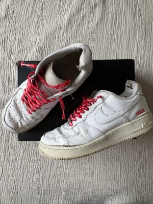 Nike Air Force 1 x Supreme vita sneakers - Säljer ett par gamla Nike Air Force 1 Supreme. Skorna är använda och slitna och därför säljer jag billigt, men de sitter fortfarande väldigt bra och är sköna att gå med. 