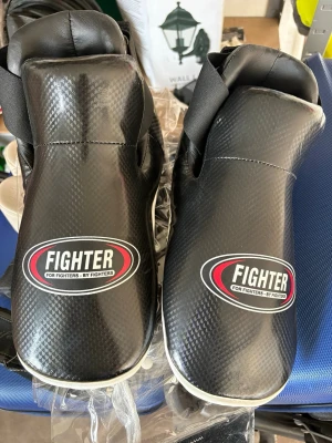 Svarta kampsportsskydd Fighter XL - Säljer ett par svarta kampsportsskydd från Fighter i storlek XL. De har en snygg kolfibermönstrad yta, bred kardborrestängning och IMT Safety-skydd för extra säkerhet. Perfekta för sparring och träning inom t.ex. karate eller taekwondo. De är helt nya och oanvända