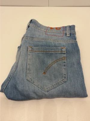 Dondup jeans  - Säljer ett par ljusblå jeans i klassisk rak modell. Jeansen har en bakficka med dekorativ söm och bälteshällor. Tillverkade i denim med en snygg tvättad look. Perfekta för en avslappnad och trendig stil.