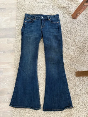 Mörkblå bootcut jeans 27/32 - Snygga mörkblå bootcut jeans! Säljer då dom tyvärr är för små. Jeansen har hög midja och utsvängda ben, perfekta för en trendig och avslappnad look. Tillverkade i denim med en skön passform.
