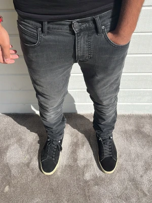 Lee jeans mörkgrå - Tja! Snygga grå Lee jeans i den populäraste modellen Luke som är en slim passform med utrymme. Modellen på bilden är 173cm och väger 74kg. Mörkgrå färg, inga defekter och bra kvalle. Storlek: W30/L32. 94% bomull 4% polyester och 2% elastan. Hör av dig! 