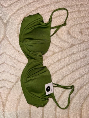 Grön bikiniöverdel med tunna band - Snygg grön bikiniöverdel med tunna axelband och lätt vadderade kupor. Bikinin har en enkel och stilren design som passar perfekt till sommaren. Materialet känns mjukt och följsamt mot huden. Helt oanvänd. 