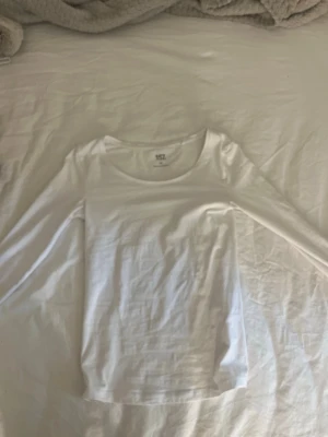 Vit långärmad topp från 157 - En basic vit långärmad topp från 157 med rund halsringning. Tillverkad i mjuk bomull med enkel och clean design, perfekt att styla lager på lager eller bära som den är. Passformen är normal och materialet känns bekvämt mot huden.
