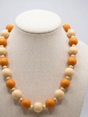 Beige och orange pärlhalsband - Snyggt halsband med stora runda pärlor i beige och orange, varvade med mindre pärlor. Halsbandet har en enkel och retro känsla, perfekt för att ge din outfit en färgklick. Materialet ser ut att vara trä eller plast.