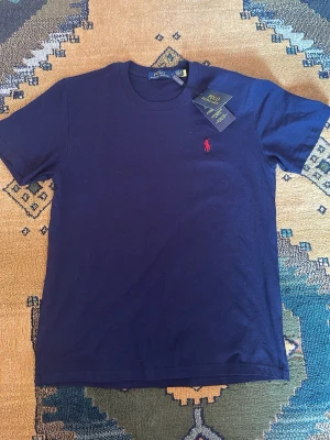 Mörkblå t-shirt från Polo Ralph Lauren - Klassisk mörkblå t-shirt från Polo Ralph Lauren. Jag säljer den för att den är ganska liten för mig har aldrig använt den. Priset kan diskuteras!!✅