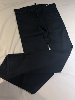 Svarta slim jeans från Dsquared2 - Snygga svarta slim fit jeans från Dsquared2, tillverkade i Italien. Klassisk femficksmodell med knappgylf och diskreta sömmar. Perfekta för dig som gillar en stilren och modern look.