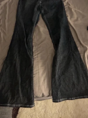 Svarta utsvängda jeans från Gina Tricot - Säljer ett par svarta jeans från Gina Tricot med riktigt utsvängda ben. Jeansen har klassisk femficksdesign och är tillverkade i denim. Perfekta för dig som gillar retrostil och vill sticka ut med en cool siluett. Pris går att diskutera