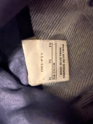 Svart Nike Dri-FIT sporttröja XL - Säljer en svart sporttröja från Nike med Dri-FIT-material som transporterar bort fukt. Tröjan har en diskret Nike-logga framtill och är tillverkad i ett mjukt, stretchigt tyg som passar perfekt till träning eller löpning.