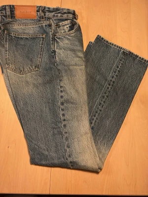 Blå raka jeans från BLK DNM - Säljer ett par klassiska blå jeans från BLK DNM med rak passform och fem fickor. Jeansen har en snygg tvättad look och är gjorda i slitstark denim. Perfekta för dig som gillar en tidlös och avslappnad stil.