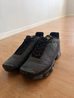 Nike TN - Säljer ett par svarta Nike TN sneakers med futuristisk design och synliga luftkuddar i sulan. Skorna har svarta snören, diskreta detaljer och en robust sula med Tuned Air-teknologi. Perfekta för dig som gillar streetwear och sportig stil.
