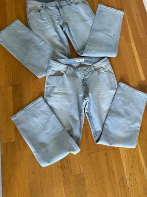 Ljusblå raka jeans från STAY - Säljer två par ljusblå jeans från STAY med klassisk femficksmodell och raka ben. Jeansen har bälteshällor och stängs med knapp och dragkedja. Perfekta för en avslappnad och trendig look.     Färg: ljusblå denim/light blue wash med slitna detaljer. Storlek: L. Modell: Lover Light Ripped.         Endast provade