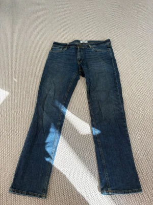 Blå jeans från Jack & Jones - Snygga blå jeans från Jack & Jones med klassisk femficksdesign och regular fit. Jeansen har normal midja, raka ben och är tillverkade i ett slitstarkt denimtyg. Perfekta för en avslappnad och trendig look.