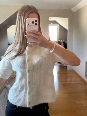 Vit stickad kortärmad kofta Gina Tricot - Mysig vit stickad kofta från Gina Tricot med korta ärmar och knappar framtill. Tröjan kommer inte längre till användning men är inte använd en stor del🤍