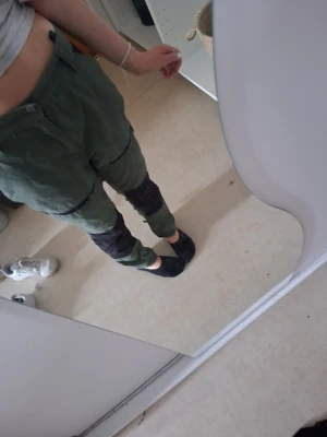 Gröna cargobyxor med svarta detaljer - Snygga cargobyxor i militärgrönt med svarta förstärkningar över knän och bak. Byxorna har flera fickor och en avslappnad passform. Perfekta för dig som gillar streetwear eller outdoor-vibe. Materialet känns slitstarkt och byxorna har dragkedja och knapp i midjan.💕