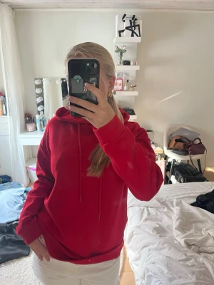 Röd hoodie från Stradivarius - Säljer en snygg röd hoodie från Stradivarius i storlek S. Hoodien har en klassisk huva med dragsnören och ribbade muddar vid ärmslut och nederkant. Perfekt för en chill och avslappnad stil. Materialet är mjukt och skönt mot huden.