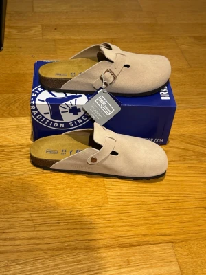 Beige Birkenstock Taupe - Birkenstock Boston Taupe – Säljes  ✅ Modell: Birkenstock Boston ✅ Färg: Taupe ✅ Storlek: 44 ✅ Skick: andvända fåtal gånger o inga tecken på andvänding.   ✅ Originalkartong följes såklart med samt två dustbags till birkenstock Boston tofflorna.  ✅ Bekväma och stilrena – passar till både vardag och fritid ✅ Populär och eftertraktad modell   