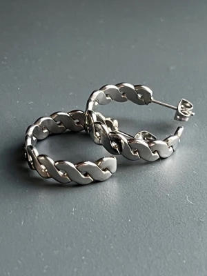 Nya Eleganta Hoops Kedjeörhängen | Kirurgiskt Rostfritt Stål Nickelsäkra | Från Svenska Lois Lane | Butikspris 350 kr - Helt nya och oanvända hoops från svenska Lois Lane i nickelsäkert kirurgiskt stål. Den flätade kedjedesignen ger en modern men tidlös look som passar allt från minimalistisk stil till streetwear. Lätta och bekväma att bära hela dagen. Diameter ca 2 cm. Butikspris ca 350 kr – ett fint tillfälle att få ett kvalitetssmycke till ett betydligt lägre pris. Jag erbjuder bundlerabatt vid köp av flera föremål.