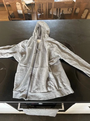 Grå hoodie från Under Armour - Säljer nu denna hoodie då den va lite stor för mig fi k den i julklapp förra året men har inte orkat lägga upp den ännu använd 3-4 gånger kanske 