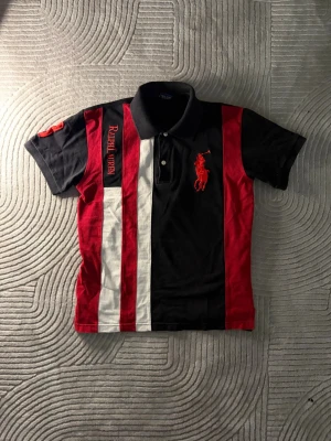 Ralph Lauren piké - Svart pikétröja med röda och vita ränder. Tröjan har en stor broderad logga på bröstet och även en trea på axeln. Tröjan är i storlek M och passar perfekt på ungefär 170-180 beroende på hur du vill att den ska sitta. Fräsch tröja utan synliga defekter. I kragen står det även Ralph lauren som gör den extra unik. Har även fler liknande ralphlauren pikéer i andra storlekar och färger på min profil så gå in och kika vetja! Och såklart om man köper fler blir priset billigare 😉Skriv vid funderingar 👍