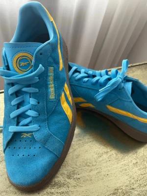 Reebok Club C💙💛 BRA SKICK! - Säljer dessa feta Reebok sneakers i modellen Club C Grounds UK!🤩 De är sköna och har klassisk gummisula. Skorna är i oerhört bra skick, OBS bilden att de har ett svagt märke på nosen av vänstra skon. Jag säljer dem eftersom de tyvärr inte kommer till användning och förtjänar en ny ägare🙌🙌 Pris kan diskuteras vid en snabb affär!🤝 Skicka ett meddelande om du undrar över något!