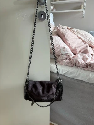 Svart axelväska med kedjerem - Snygg svart axelväska med grov silverfärgad kedjerem och mjukt material. Väskan har leopardmönstrat innerfoder och flera fack med dragkedja. Perfekt storlek för det viktigaste och ger en cool vibe till din outfit.