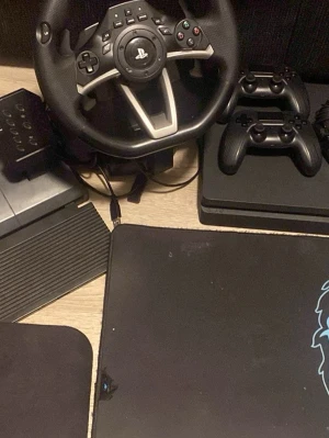 Ratt och pedaler till PlayStation - Säljer en svart ratt med PlayStation-logga och tillhörande pedaler, perfekt för racing- och bilspel. Ratten har flera knappar och en robust design i plast och gummi. Passar till PlayStation-konsoler och ger en realistisk spelupplevelse.