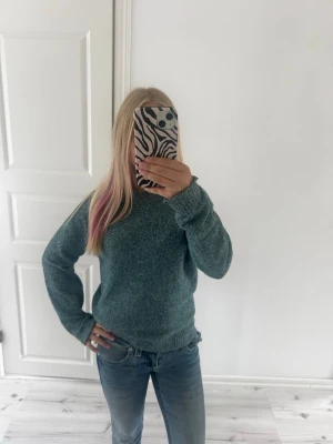  Kashmir tröja  - Mysig mörkgrön stickad tröja med rund halsringning och långa ärmar. Tröjan har ribbstickade muddar vid ärmslut och nederkant. Perfekt för kyligare dagar och enkel att matcha med jeans eller kjol.