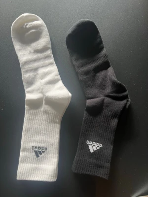 Svarta och vita ribbade strumpor perfekt för fotboll eller gym osv - Två par klassiska strumpor i svart och vitt med ribbad struktur och diskret logga framtill. Perfekta för dig som vill ha en stilren och sportig look. Strumporna är mjuka och bekväma, passar till både sneakers och boots. Passar perfekt till fotbollsspelare eller till gym.      1 par 60 eller båda 100.