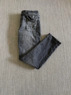 Grå slim fit jeans från Jack & Jones - Snygga grå slim fit jeans från Jack & Jones med klassisk femficksdesign och dragkedjegylf. Jeansen har en tvättad look och är perfekta för en avslappnad stil. Tillverkade i mjukt denimtyg som sitter skönt hela dagen.