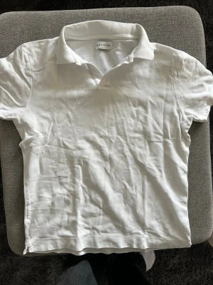 Vit pikétröja från These Glory Days - Klassisk vit pikétröja från These Glory Days i storlek small. Tröjan har korta ärmar, mjuk krage och är tillverkad i ett bekvämt bomullsmaterial. Enkel och stilren design som passar till det mesta.