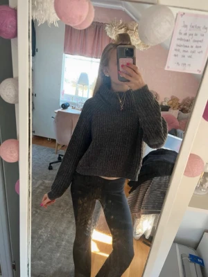 Mörkgrå stickad polotröja - Säljer en mörkgrå, ribbstickad polotröja med croppad passform och långa ärmar. Tröjan har en bred, mysig polokrage och är perfekt för kyliga dagar. Materialet ser mjukt och varmt ut, och modellen är både trendig och bekväm. Storlek 158/164