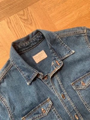 Nudie Jeans Denim Jacket - Cool vintage jeansjacka av märket Nudie Jeans med en klassisk tvåfacks design på framsidan. Storlek XS samt true to size, modellen är 178 cm lång och väger 65 kg.  Skriv vid frågor och funderingar!