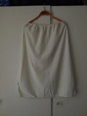 Vit långkjol med enkel design - Enkel och stilren vit långkjol med rak passform och resår i midjan. Kjolen är gjord i ett lätt tyg som passar perfekt till varmare dagar. Inga synliga detaljer eller mönster, vilket gör den lätt att matcha med olika toppar.