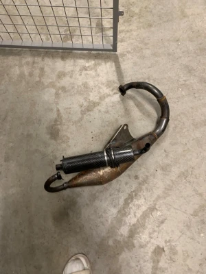 Stage6 avgassystem till moped - Säljer ett avgassystem från Stage6 till moped. Utrustad med en svart kolfiber-liknande ljuddämpare och böjd metallpipa. Passar dig som vill uppgradera din moppe med sportigare ljud och look.