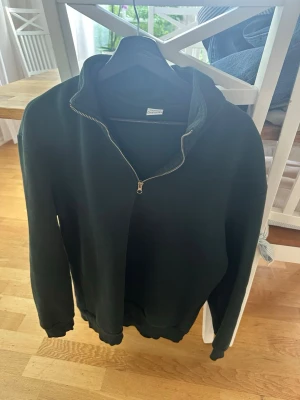 Mörkgrön hoodie från DeFacto - Mörkgrön hoodie från DeFacto i storlek M. Klassisk modell med dragkedja framtill och långa ärmar. 
