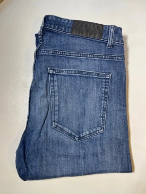 Blå jeans - Snygga blå jeans i klassisk tvätt med normal midja och smal passform. Jeansen har fem fickor, bälteshällor och silverfärgade nitar. Perfekta för dig som gillar en enkel och stilren look. Materialet är mjukt och stretchigt jeans. Storlek:W32, L30