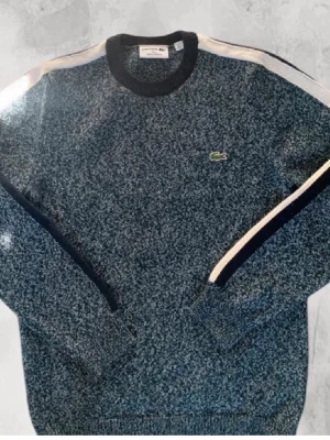 Lacoste tröja - Lacoste Stickad Tröja  Stilren melerad Lacoste-tröja i exklusiv stickad kvalitet. Helt ny och aldrig använd. Clean och lättmatchad modell som passar perfekt till en stilren outfit.  • Storlek S • Melerad • Stickad • Helt ny • Nypris ca 3 000 kr  Skickas inom 24H📦
