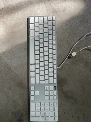 Apple USB-tangentbord med numerisk del - Säljer ett stilrent Apple-tangentbord i aluminium och vit plast med numerisk del. Ansluts via USB och har låg profil på tangenterna. Perfekt för dig som gillar minimalistisk design och smidiga skrivupplevelser till datorn. Saknar dock en tangent, priset kan förhandlas.