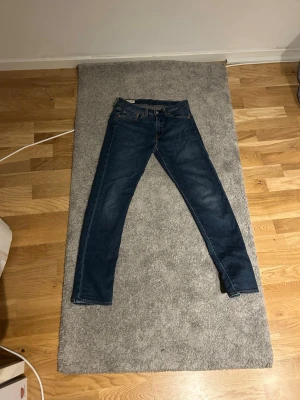 Levi's 502 blå jeans W28 L32 - Säljer ett par klassiska blå Levi's 502 jeans i storlek W28 L32. Jeansen har rak passform, fem fickor och snygga kontrastsömmar. Perfekta för dig som gillar en tidlös och avslappnad stil.
