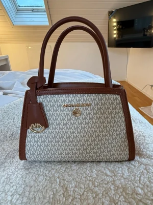 Michael kors handväska  - Säljer denna Michael kors väskan då ja ej får andvänding för den. Köpt för länge sen och andvänt några gånger bara. Den är i bra skick förutom att märket har några skador, annars är väskan helt som ny:)