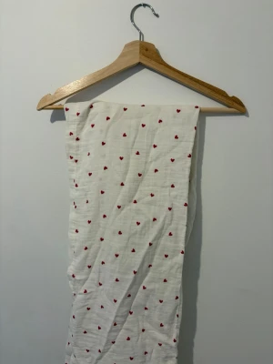Vita pyjamasbyxor med röda hjärtan - Säljer ett par vita pyjamasbyxor med små röda hjärtan över hela tyget. Byxorna har resår i midjan och är gjorda i ett mjukt, tunt material som känns skönt mot huden. Perfekta för mysiga hemmakvällar eller lata morgnar. Storlek 170 men sitter som xs