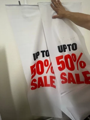 Vita och röda tygbanderoller - Säljer flera vita och röda banderoller i tyg med tryck i svart och rött. Texten på banderollerna lyder bland annat 'UP TO 50% SALE' och 'FASHION SALE 50%'. Perfekt för att skylta rea eller kampanj i butik eller på event. Kommer även sälja metallen som används för att hänga de. Pris kan diskuteras.