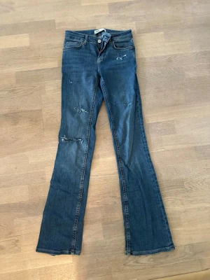 Blå bootcut jeans från ZARA - Snygga blå bootcut jeans med slitningar och lägre midja ifrån Zara