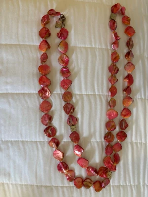 Rosa pärlhalsband med oregelbundna pärlor - ca 61cm längd,snö,själva märket snö 5st på halsbandet är tillfredställande (se bilder) vet inte hur man putsar sånt,övriga halsbandet är fint! Unikt korall rosa halsband med oregelbundna pärlor i skimrande rosa och orange toner. Pärlorna har en naturlig, organisk form och halsbandet har metallspänne med liten bricka. Perfekt för dig som vill sticka ut med färg och form.