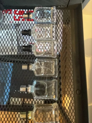 Set med små herrparfymer i glasflaskor - Säljer ett set med flera små herrparfymer i rektangulära glasflaskor. Flaskorna har olika färger på sprayhuvudet, bland annat svart och silver. Några av flaskorna har text som 'HOMME', 'DARK LINE' och 'GOLD'. Perfekt för dig som vill testa olika dofter.