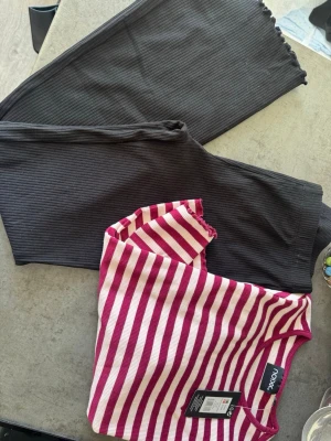 Svarta ribbade leggings med vågig kant - Säljer ett par svarta leggings i ribbat material med snygg vågig kant längst ner på benen. De är stretchiga och har en smickrande passform som sitter skönt. Perfekta till både oversized tröjor och crop tops.