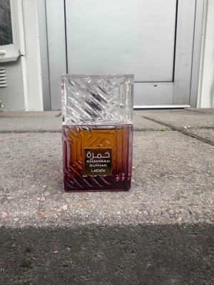 Khamrah Duft från Lattafa - Khamrah Duft från Lattafa är en parfym i en fyrkantig glasflaska med snyggt mönstrad design. Flaskan har en gradient från bärnstensfärg till lila och ett genomskinligt lock med graverat mönster. Perfekt för dig som gillar exklusiva och unika dofter.